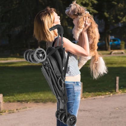 Woman holding a dog while carrying a folded pet stroller for dogs and cats outdoors.